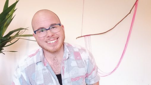 A man in his early thirties smiles warmly. He wears glasses and has a strawberry blonde beard.