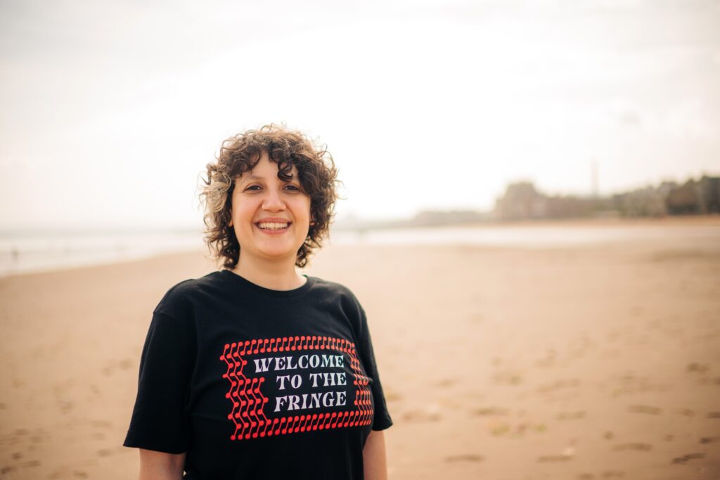 Sara Shaarawi stands on the beach at Portobello in a Welcome to the Fringe T-shirt