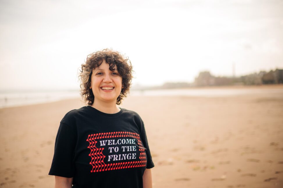 Sara Shaarawi stands on the beach at Portobello in a Welcome to the Fringe T-shirt